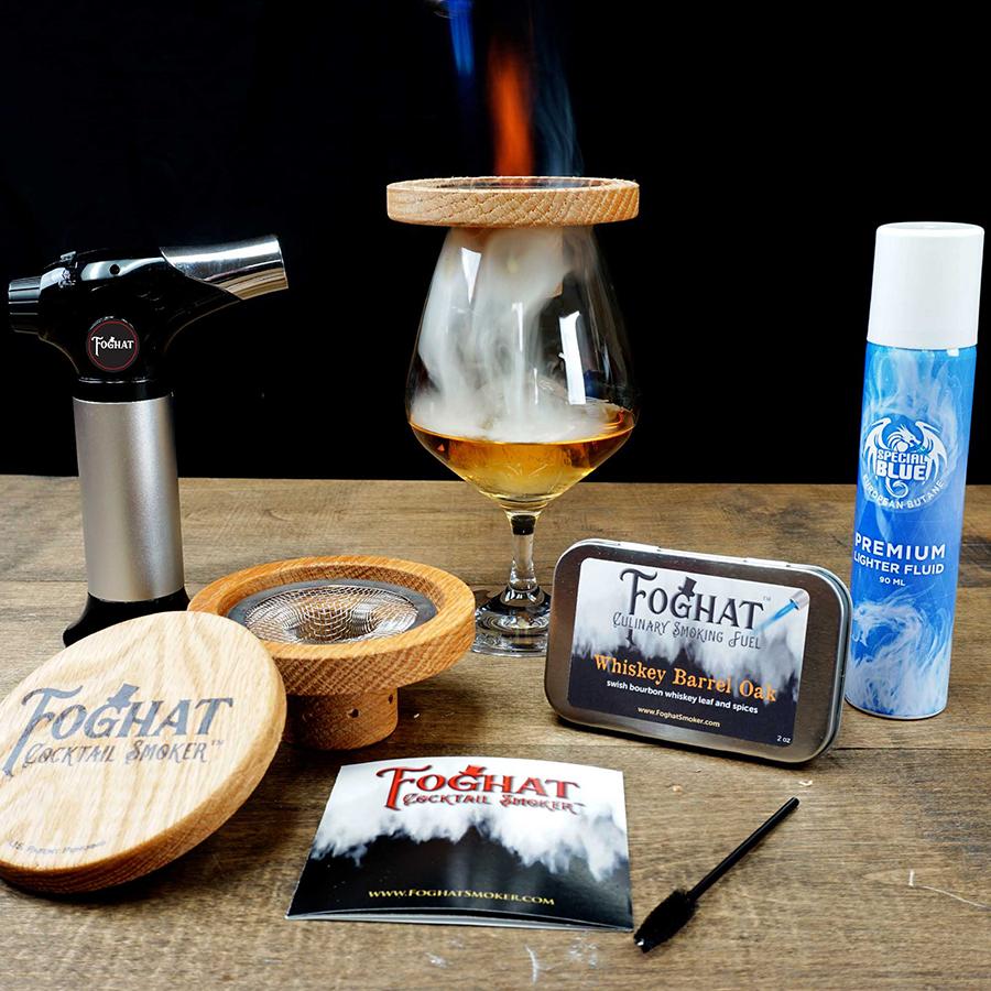 Foghat Cocktail Smoker Set - all items displayed - torch, smoker with mesh insert, instruction booklet, cleaning brush, smoking fuel tin, butane fuel and whiskey glass being smoked